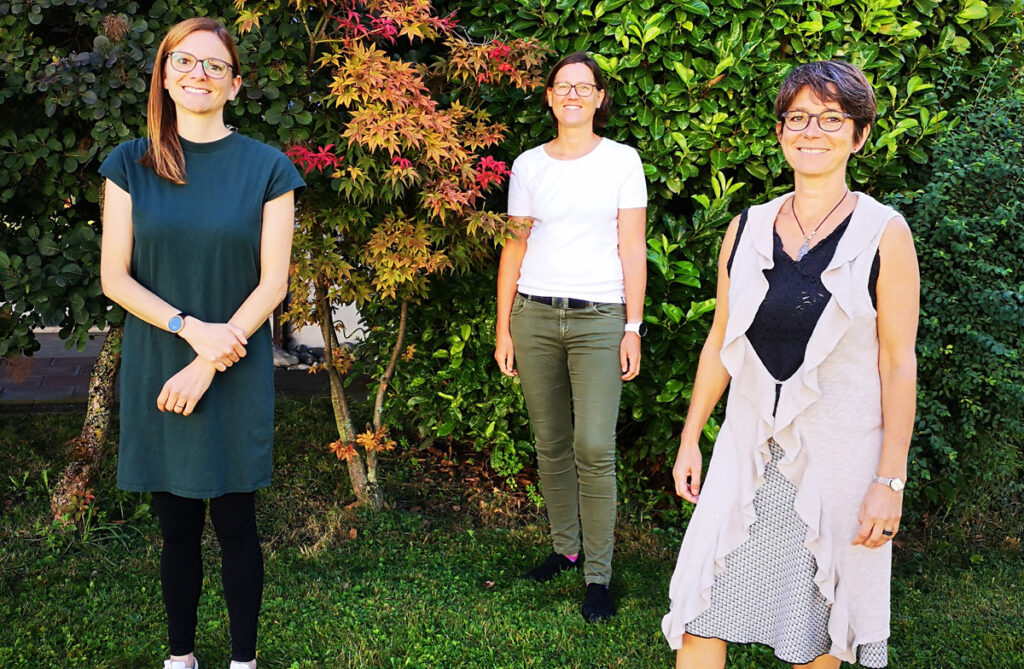 Die drei Organisatorinnen der Bilungskonferenz stehen auf einer Wiese