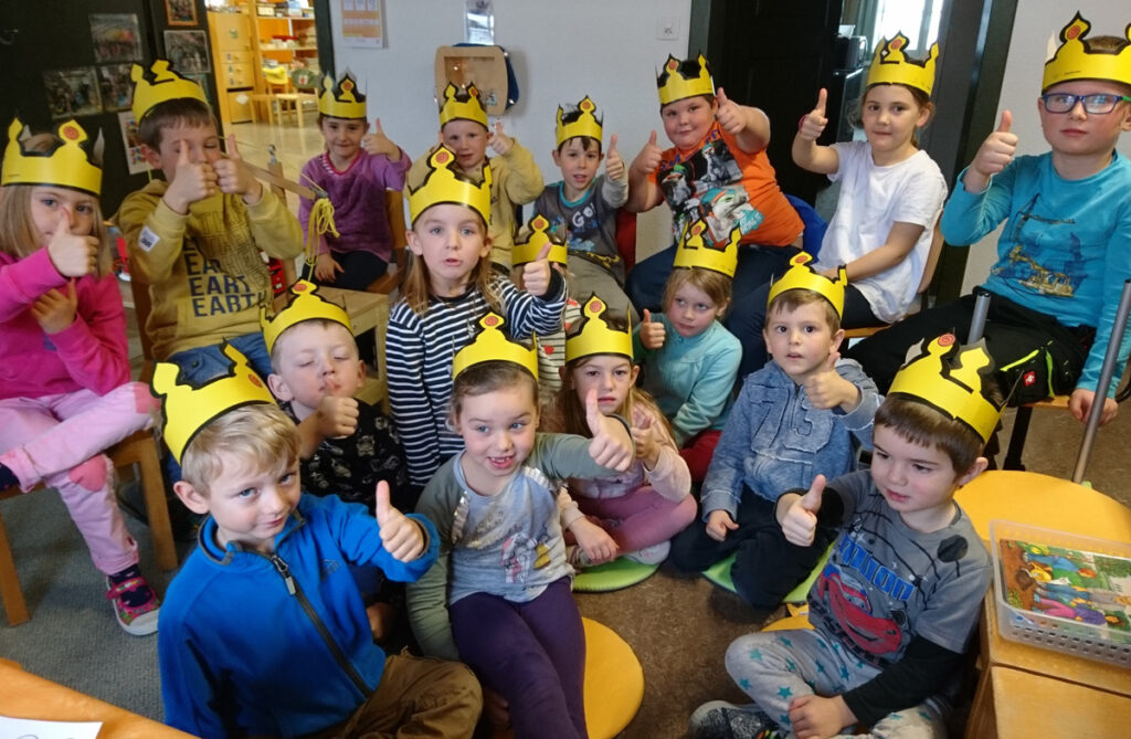 Kinder mit einer Krone auf dem Kopf zeigen den Daumen hoch